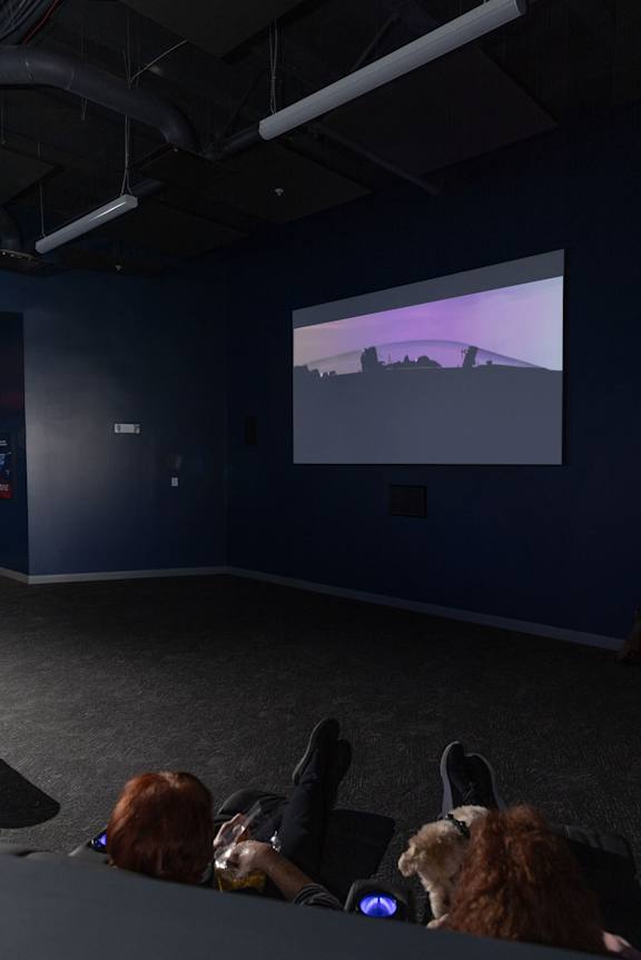 a group of people are sitting in a dark room watching a movie on a screen at The Residences at Tesson Ridge, Missouri, 63128