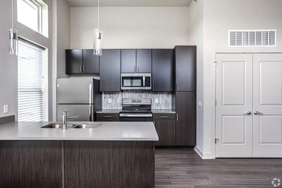 A modern kitchen with dark wood cabinets and a white countertop.