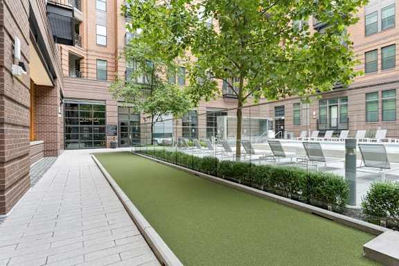 a courtyard with grass and chairs in front of a building