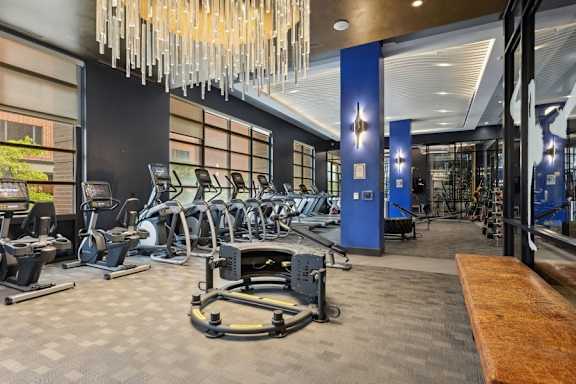 a gym with cardio machines and a chandelier