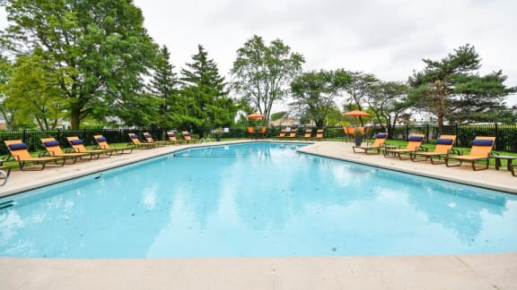 A large swimming pool surrounded by trees and lounge chairs.