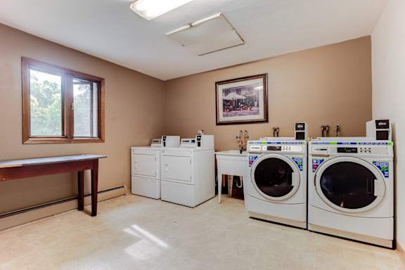 A laundry room with a washer and dryer on the right and a table on the left.