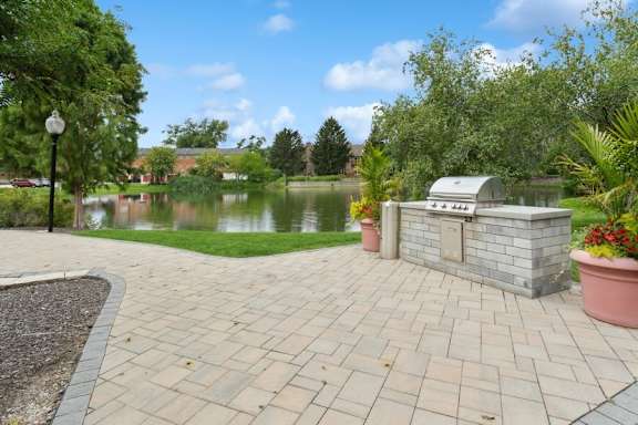 A brick walkway leads to a small building next to a pond.