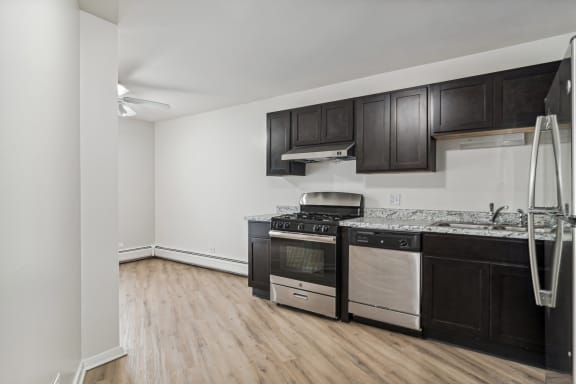 an empty kitchen with black and white appliances and wood flooring at The Reserve on Washington, Illinois