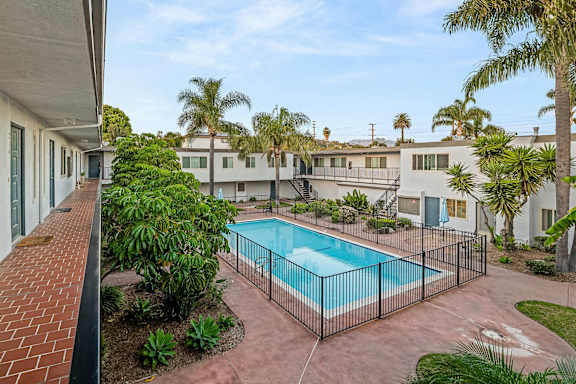 Fenced pool area with tropical landscaping and walkways at Shorehaven Townhomes Apartments, Ventura, California