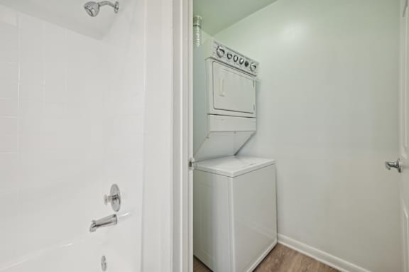 A white bathroom with a shower and a washer and dryer