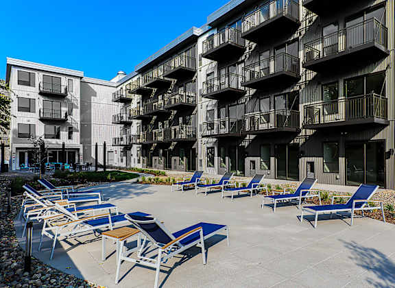 Courtyard pool area with blue lounge chairs and modern buildings at Pure Lowry Apartments, Minneapolis, Minnesota