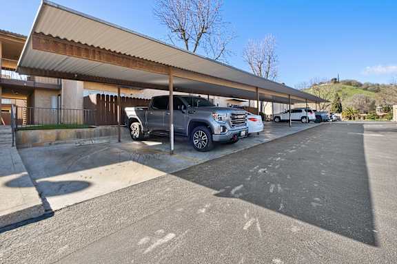 a parking lot with cars parked in front of a building  at Alturas Paso Robles Apartment Homes, Paso Robles, CA