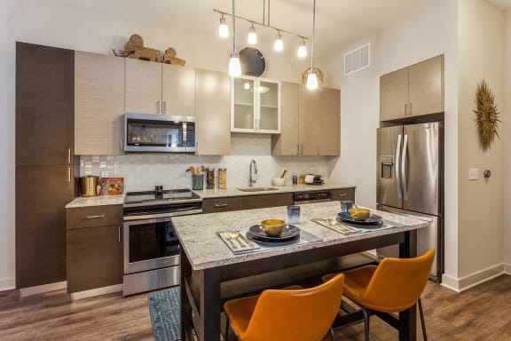 a kitchen with stainless steel appliances and an island with plates of food