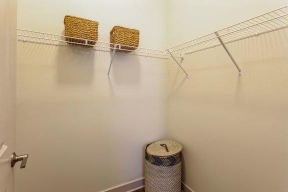 a walk in closet with two baskets and a rack on the wall