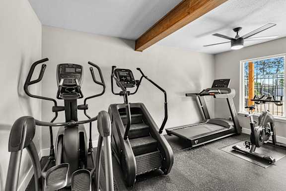 A room with a row of exercise bikes and a treadmill.