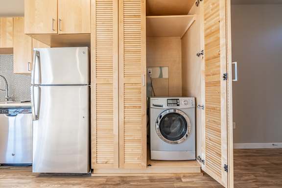 A modern kitchen with a refrigerator and a washing machine.