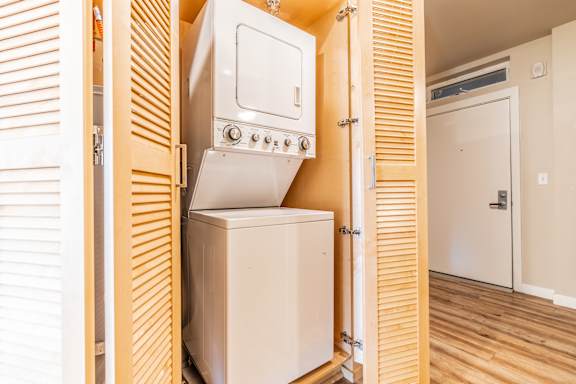 A white oven and fridge are built into a wooden cabinet.