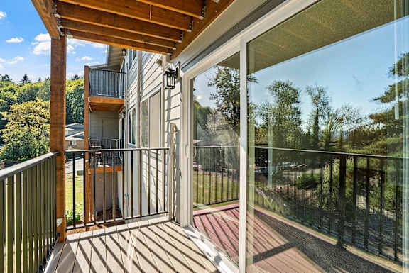 A balcony with a glass door and a wooden railing.