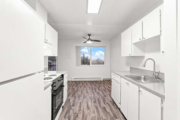A kitchen with white cabinets and a wood floor.