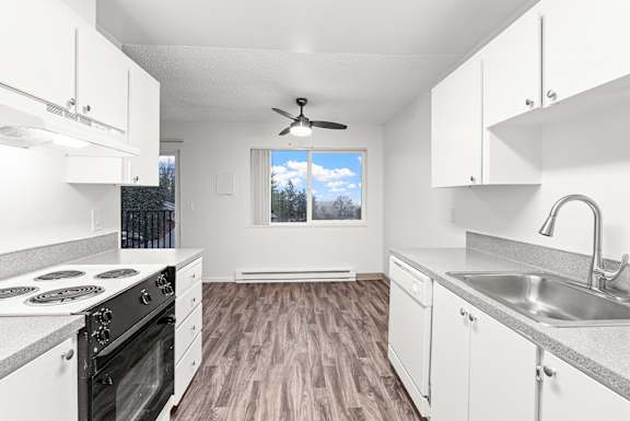 A kitchen with white cabinets and a wood floor.