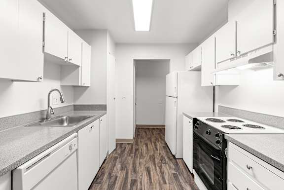 A kitchen with white cabinets and a wooden floor.