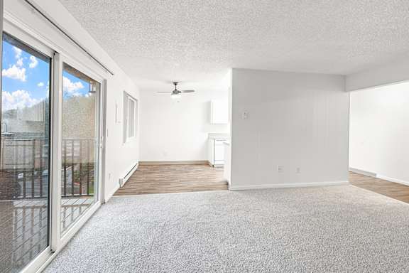 A room with a ceiling fan and a sliding glass door.