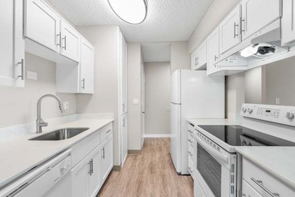 A white kitchen with a sink and stove.