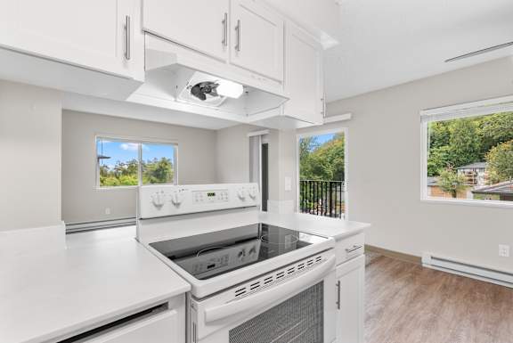 A white kitchen with a stove top oven and a double oven stove.