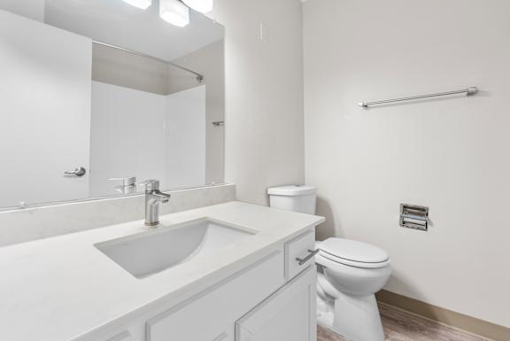 A white bathroom with a toilet, sink, and mirror.