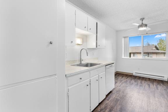 A kitchen with white cabinets and a marble countertop.