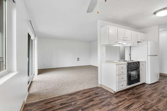 A kitchen with white appliances and wooden floors.