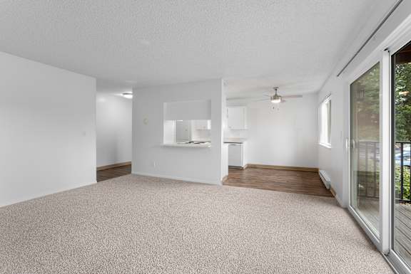 A spacious room with a carpeted floor and a ceiling fan.