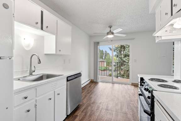 A white kitchen with wood floors and a window.