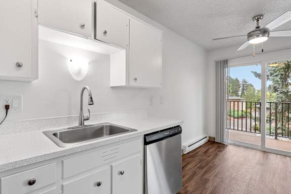A kitchen with white cabinets and a stainless steel sink.