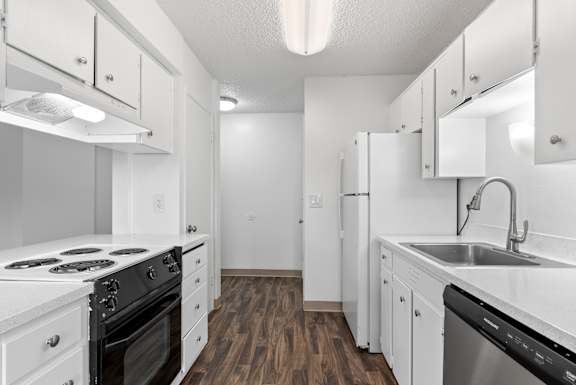 A kitchen with white appliances and wooden floors.