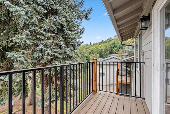 A balcony with a black railing and a wooden floor.
