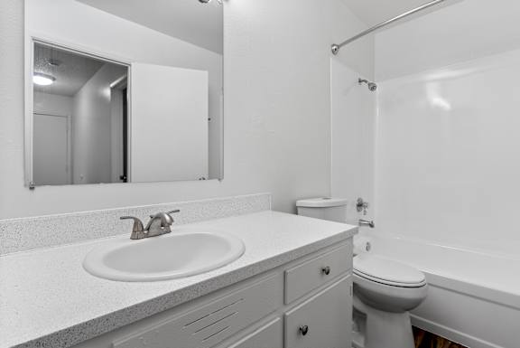 A white bathroom with a sink, toilet, and bathtub.