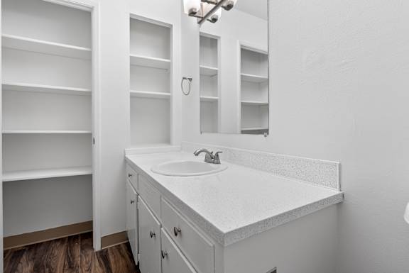 A white bathroom vanity with a sink and mirror.