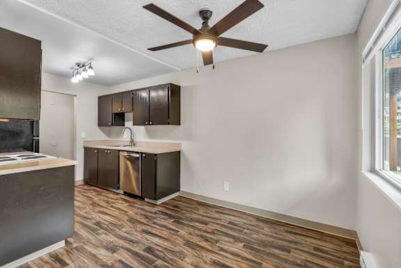 A kitchen area with a ceiling fan and wooden flooring.