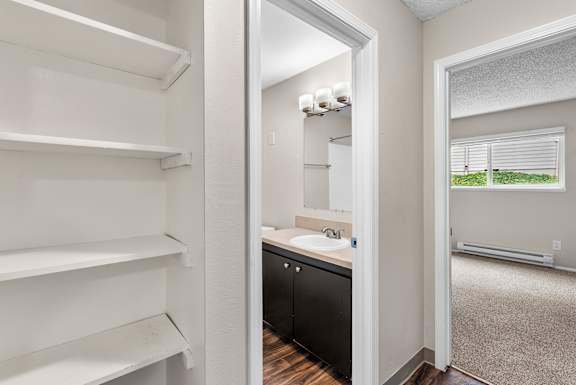 A bathroom with a sink, mirror, and a window with blinds.
