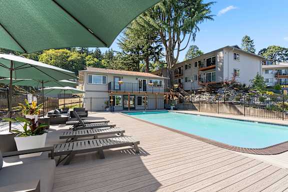 A pool surrounded by a deck with sun loungers and umbrellas.