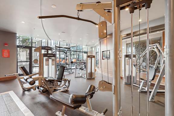 a gym with weights and other exercise equipment in a building with glass walls