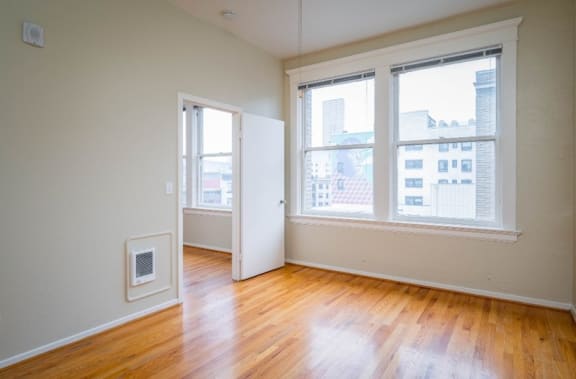 an empty room with a wood floor and three windows