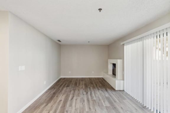 A spacious room with wooden flooring and white walls.