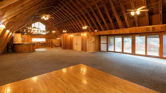 A spacious attic room with wooden floors and a large window on the right side.
