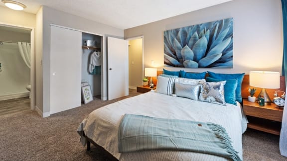A bedroom with a bed, nightstand, and a painting on the wall.