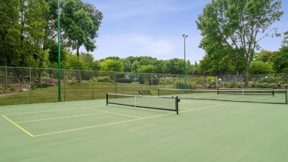 A tennis court surrounded by a fence and trees.