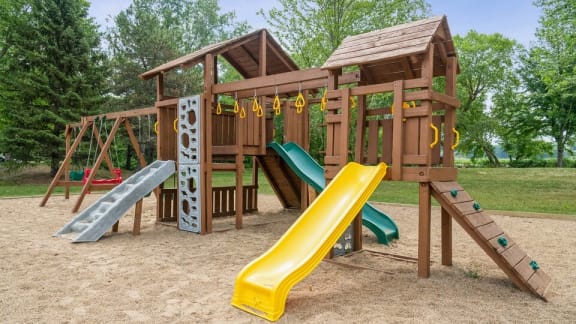 A playground with a yellow slide and a green slide.