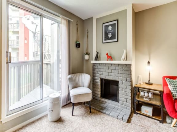 A living room with a fireplace, chair, and a window.