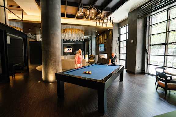 A woman is playing pool in a room with a pool table.
