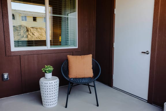 a chair and a plant on a porch in front of a door