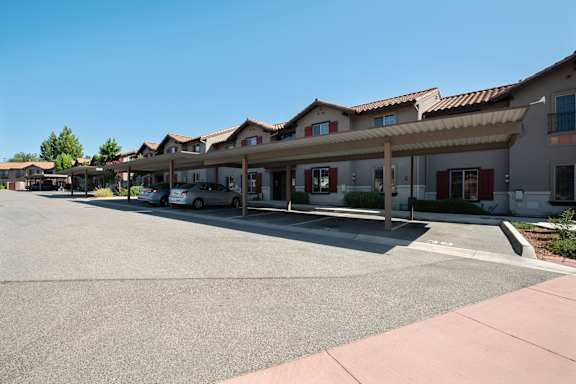 an empty parking lot in front of a hotel with cars parked in front