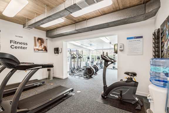 A gym with treadmills, exercise bikes and a water cooler.