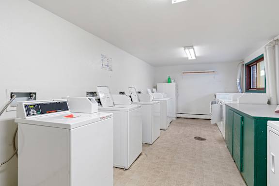 a row of washing machines in a laundry room with other washers and dryers